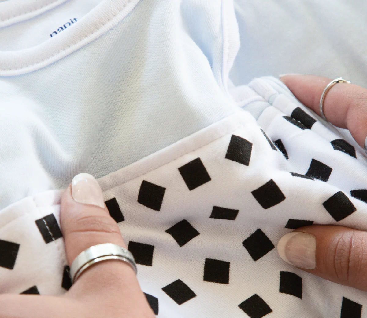 Nanit Breathing Wear Band for baby breathing motion monitoring, small size, shown on a sleeping baby in a soft sleep sack.