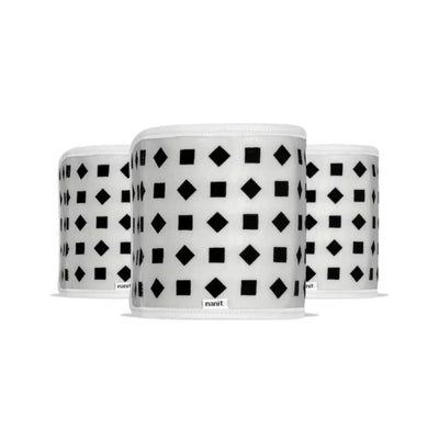 Nanit Breathing Wear Band for babies, small size, soft fabric, designed for breathing motion monitoring, shown with camera in the background.